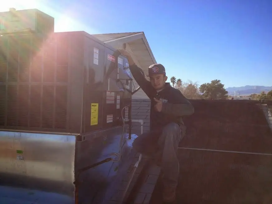 HVAC technician performing Heat Pump Repair on a rooftop unit in Yoakum